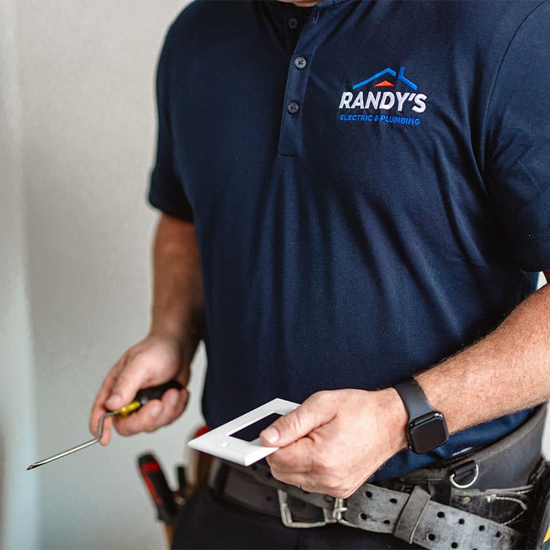 Randy from Summit Electric & Plumbing holding a screwdriver and light switch cover.