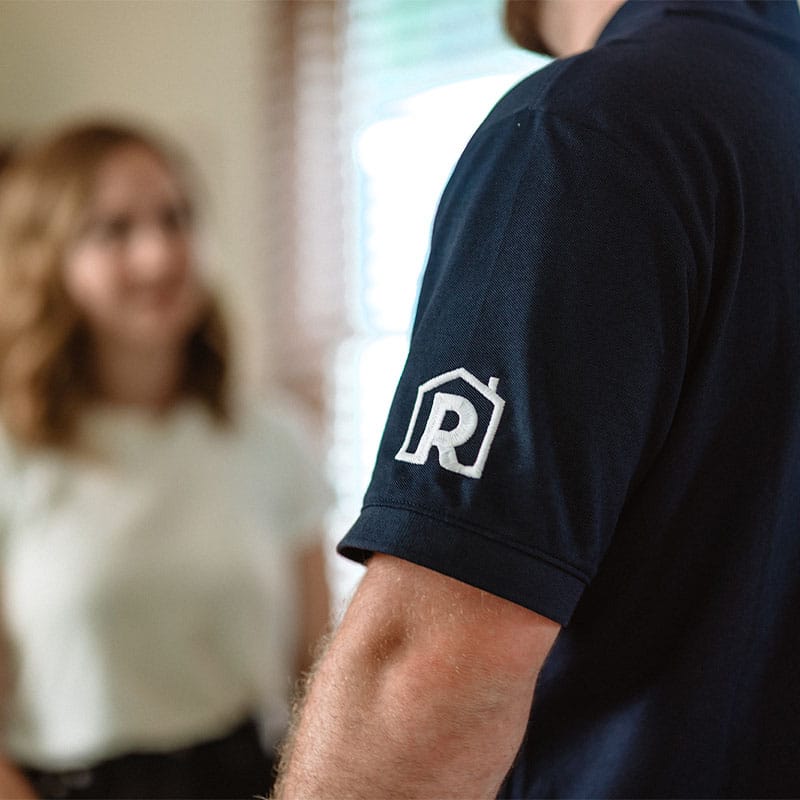 Man wearing a shirt with house logo while talking to a woman.