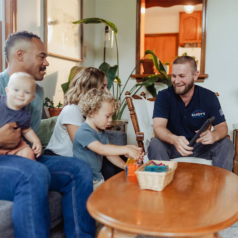 A family sitting on a couch with a professional from Summmit, discussing home services in a living room.