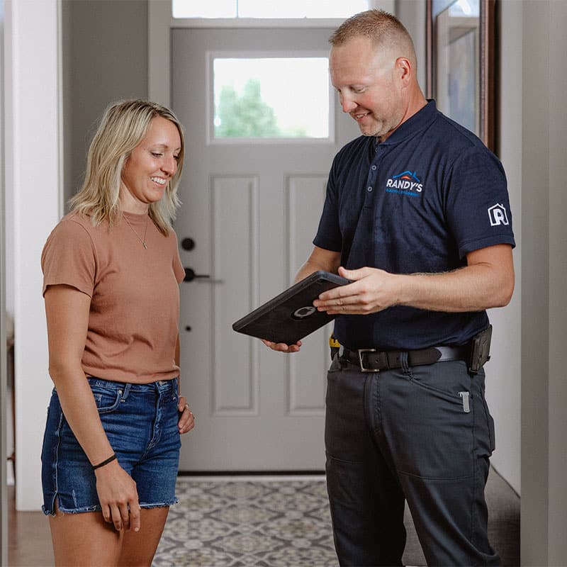 A person discussing home service with Summmit technician using a tablet in a well-lit entryway.