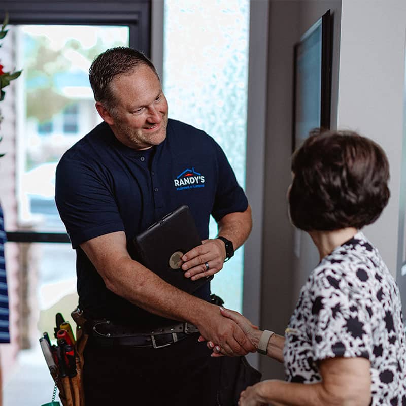 Handyman from Summmit Plumbing & Heating shaking hands with a customer indoors.