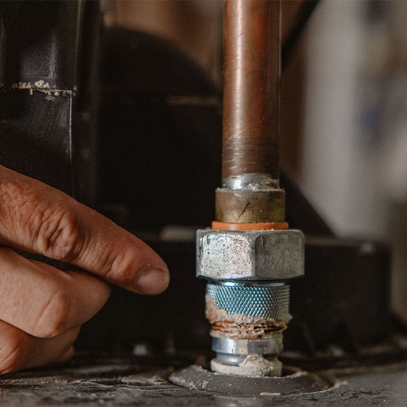Close-up of a hand adjusting a plumbing pipe fitting in a workshop setting.