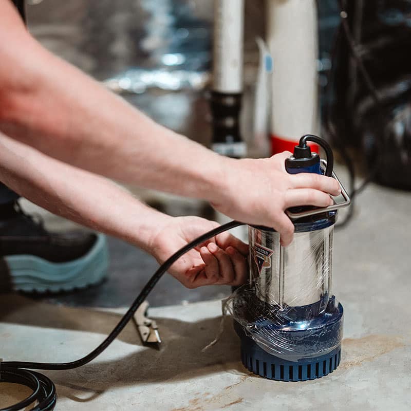 Person installing a sump pump in a basement for water management and flood prevention.