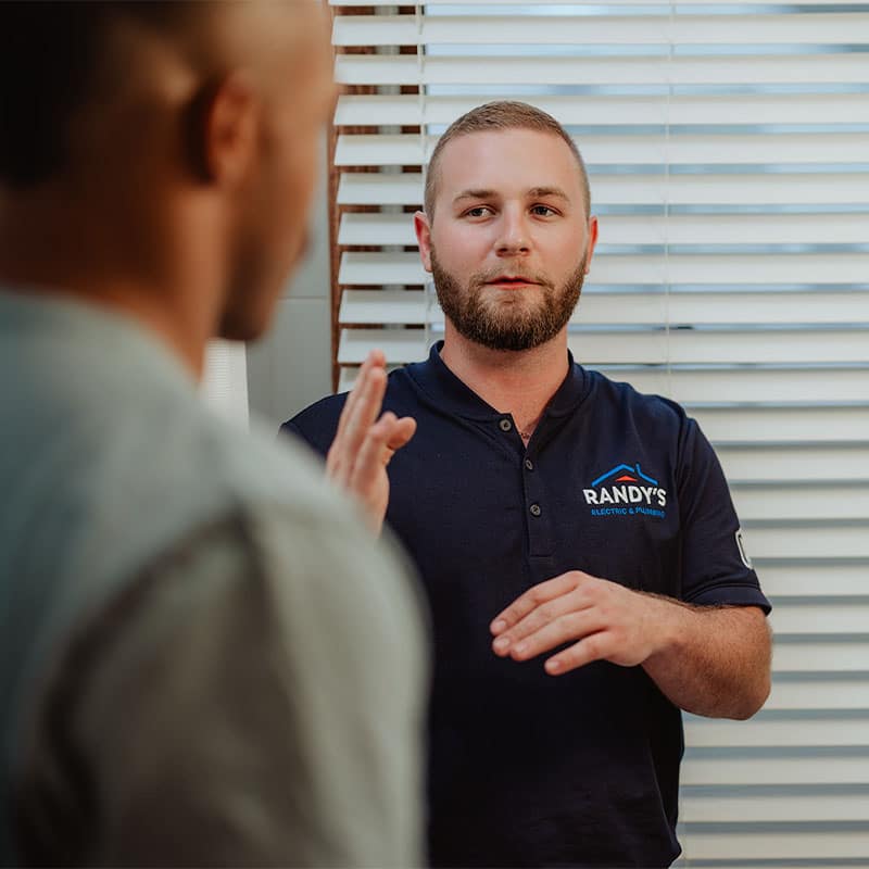 Man in Summmit uniform discussing with another person indoors near window blinds.