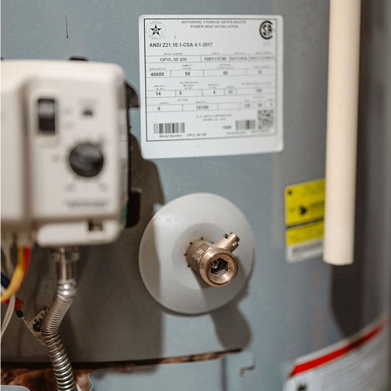 Close-up of a water heater showing valve and labels.
