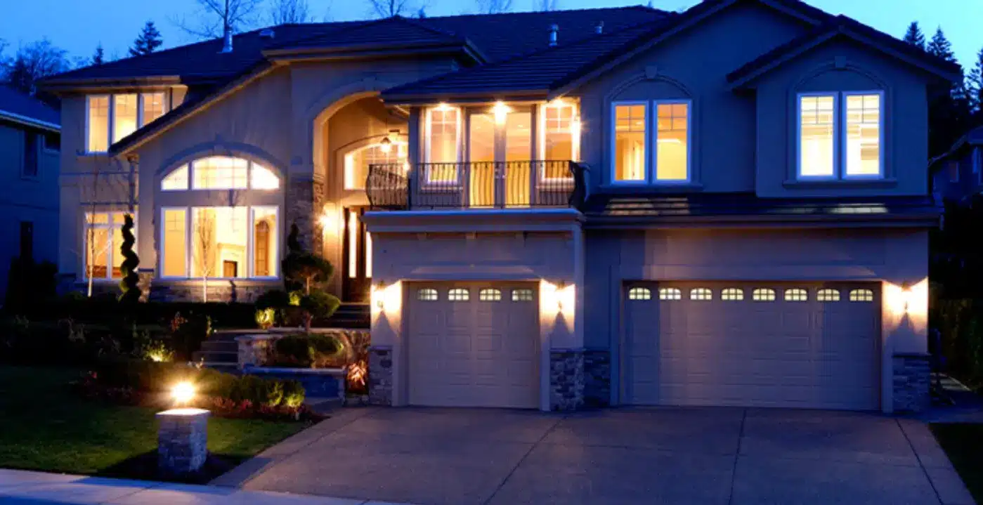 Modern two-story house illuminated at night with garage and large windows.