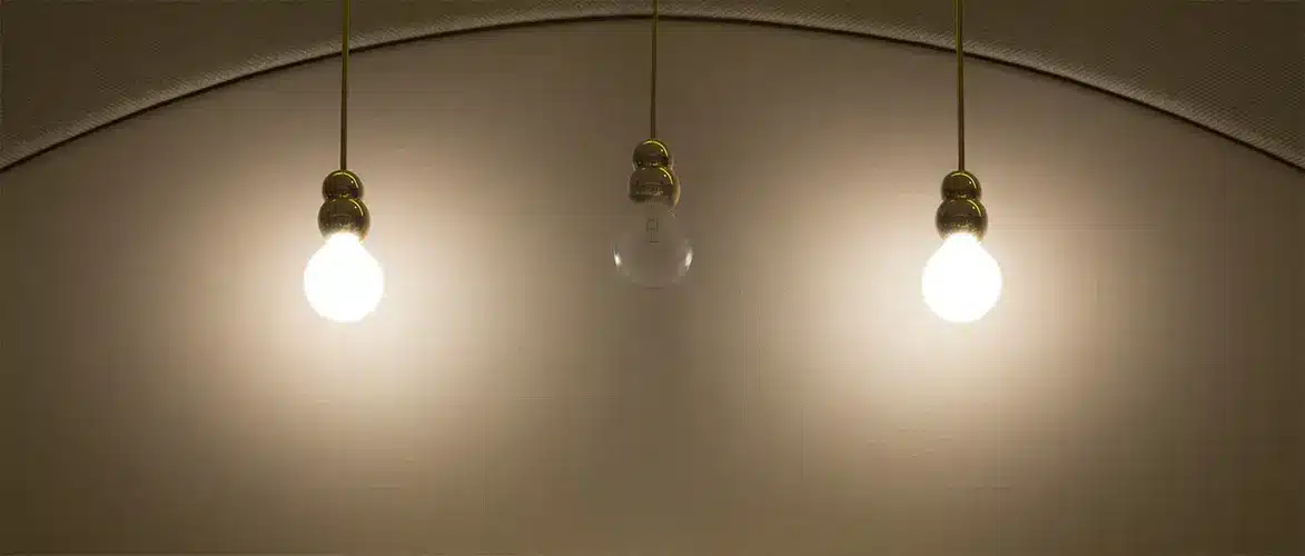 Three hanging light bulbs lit against an arched ceiling, with the center bulb unlit.