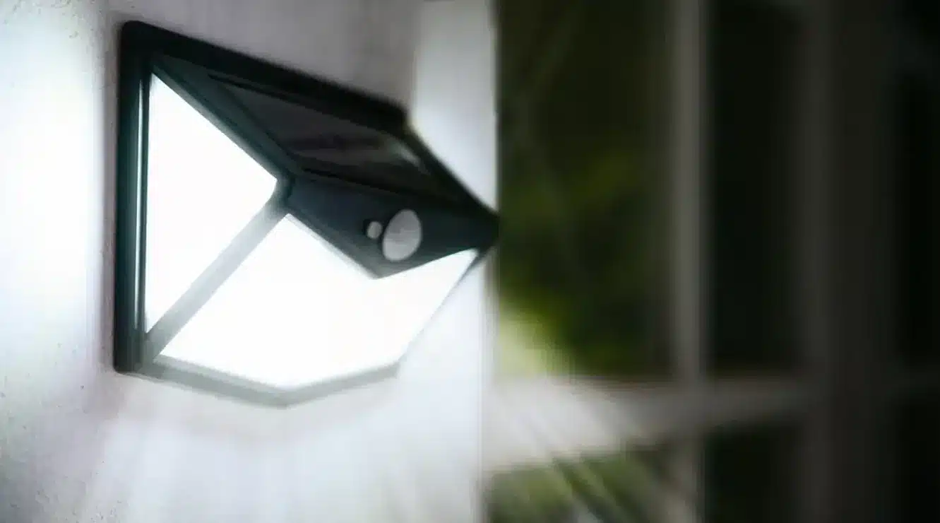 Outdoor solar-powered LED wall light glowing at night.