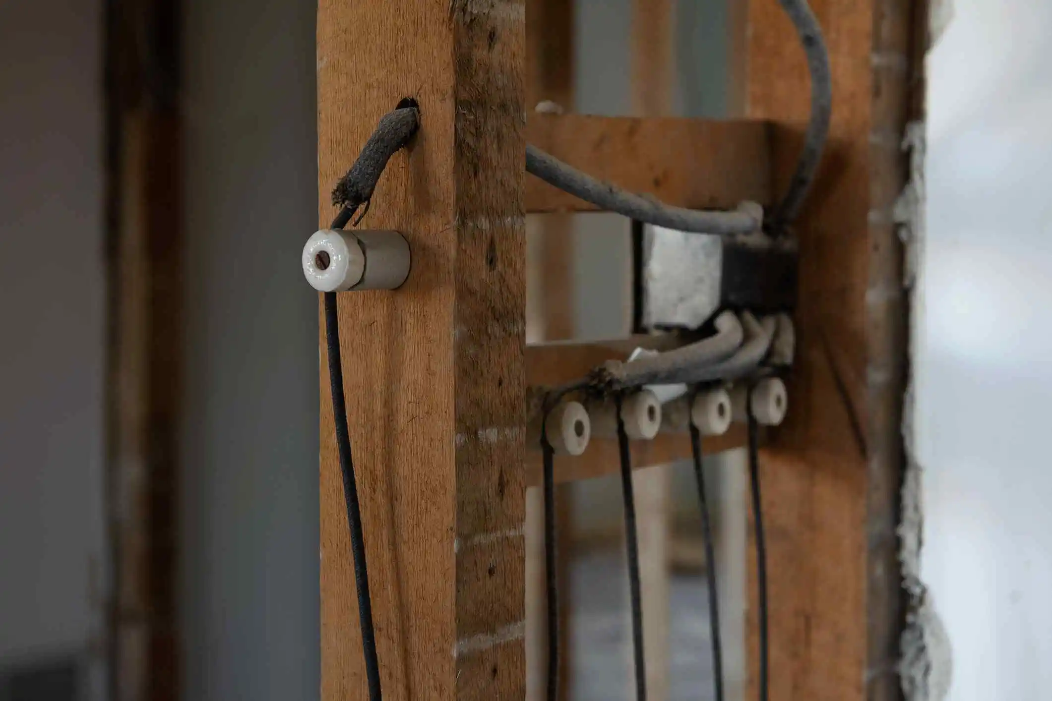 Vintage knob and tube wiring system in an exposed wooden frame, highlighting old electrical technology.