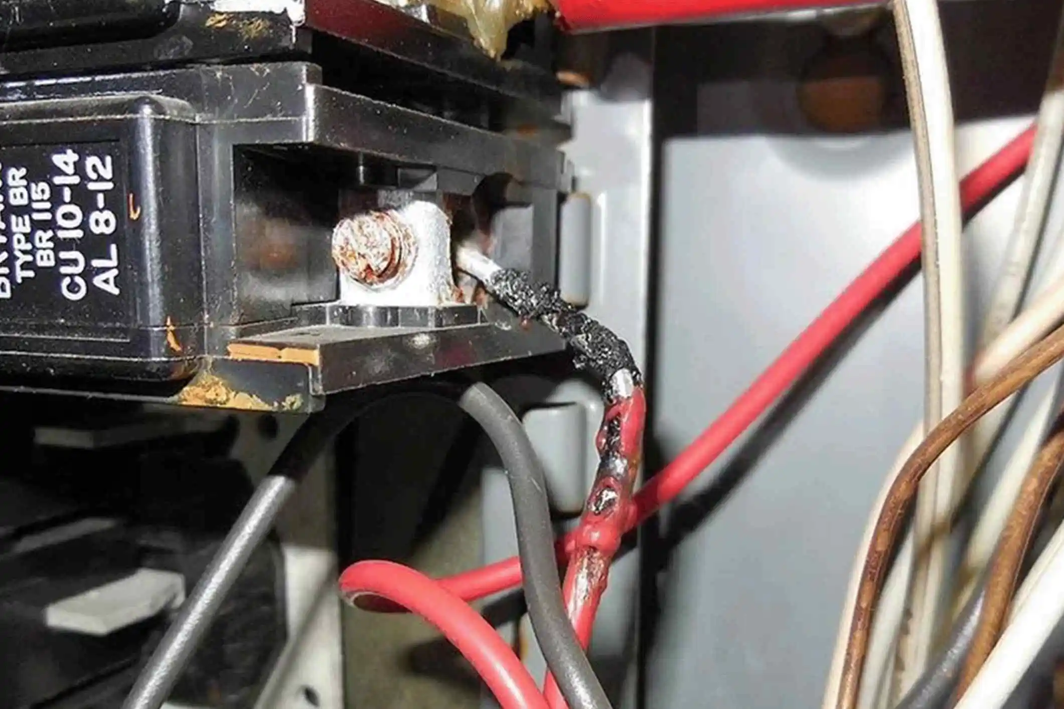Burnt electrical wire in circuit breaker showing signs of overheating hazard.
