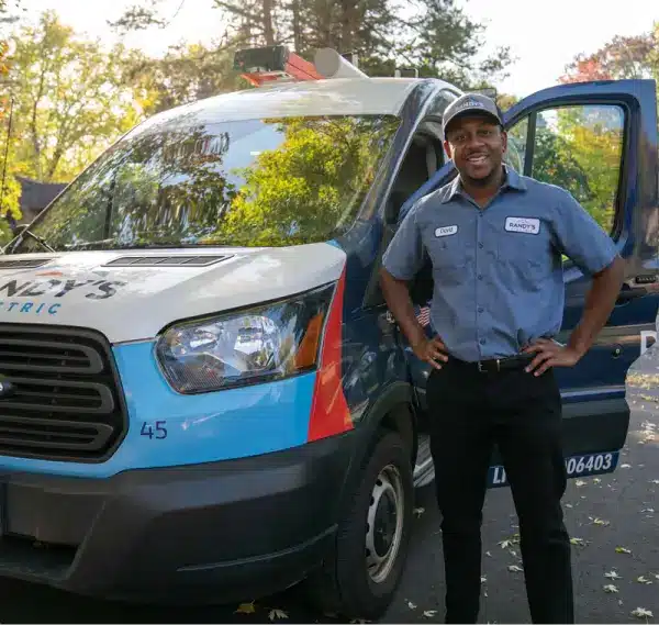 Connor standing next to Summmit Electric van with open door, wearing uniform and cap.