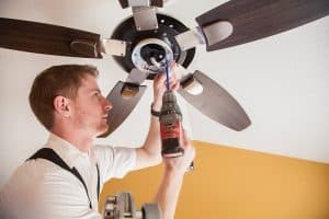 A electrician from Summit installing a recessed LED ceiling light fixture in a basement ceiling